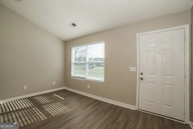 an empty room with wooden floor and window