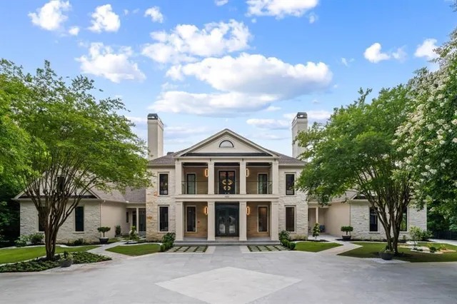 a front view of a house with a garden and trees
