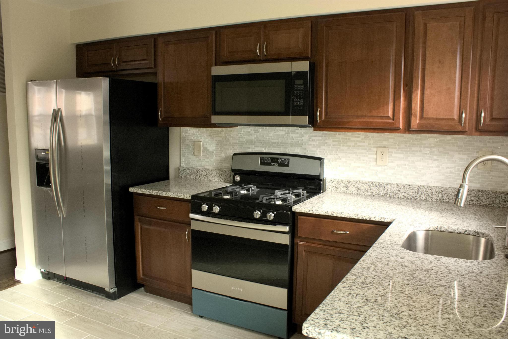 6709 Garvey Road Baltimore, MD 21237 - Photo 6 of 29 a kitchen with stainless steel appliances granite countertop a stove microwave and refrigerator
