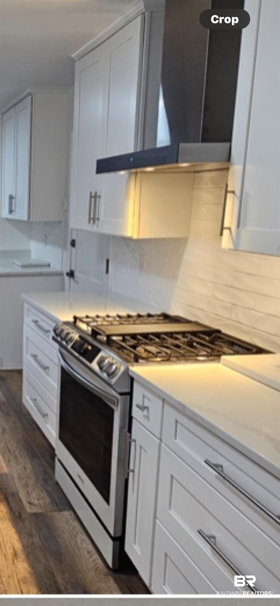 159 Conway Drive West Mobile, AL 36608 - Photo 6 of 24 Kitchen featuring stainless steel range with gas cooktop, wall chimney range hood, white cabinets, dark wood-style flooring, and decorative backsplash