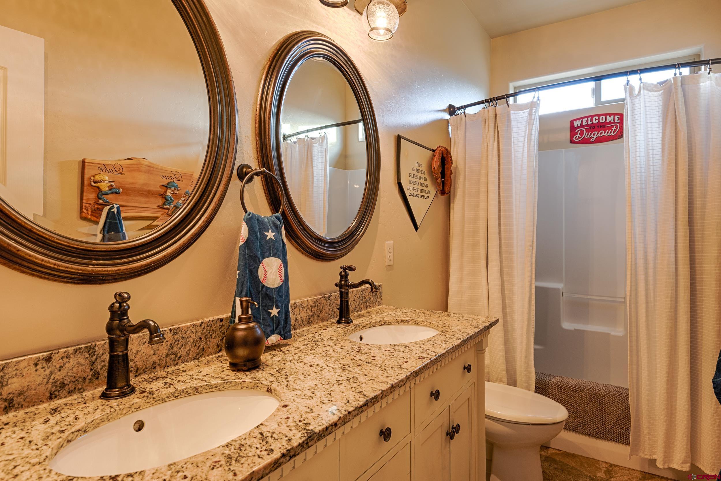 13287 6160th Road Montrose, CO 81403 - Photo 23 of 35 a bathroom with a granite countertop sink a mirror a toilet and a sink