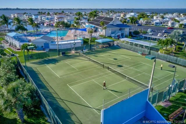 an aerial view of a tennis ground and a cars park side of the road