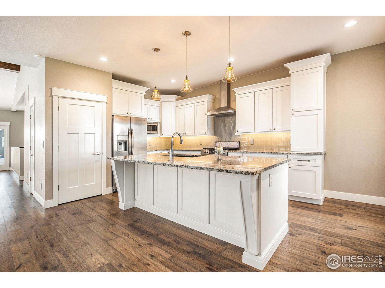 a kitchen with stainless steel appliances kitchen island wooden floors and white walls