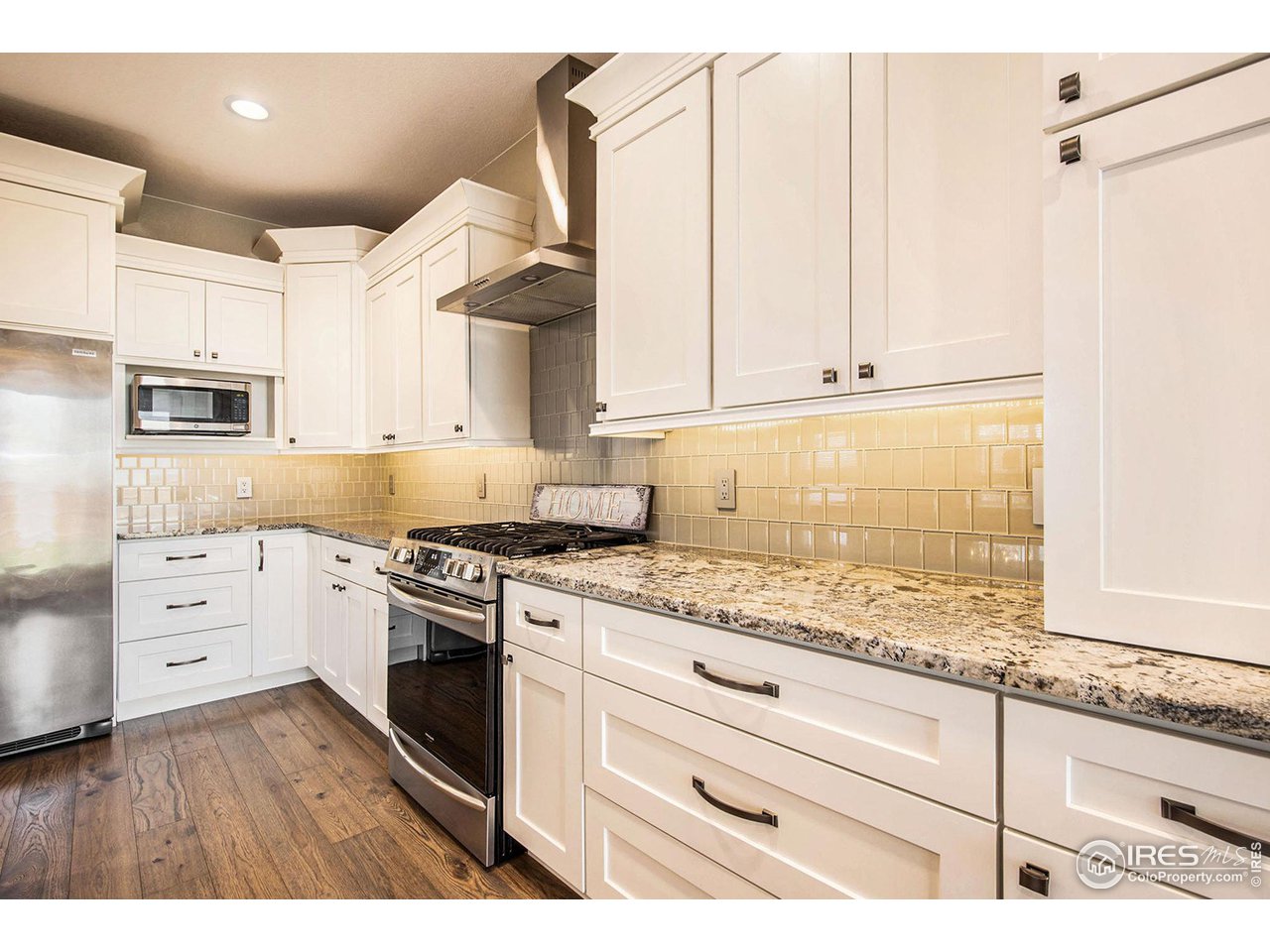 1100 Johnson Street Wiggins, CO 80654 - Photo 7 of 34 a kitchen with granite countertop white cabinets and white appliances