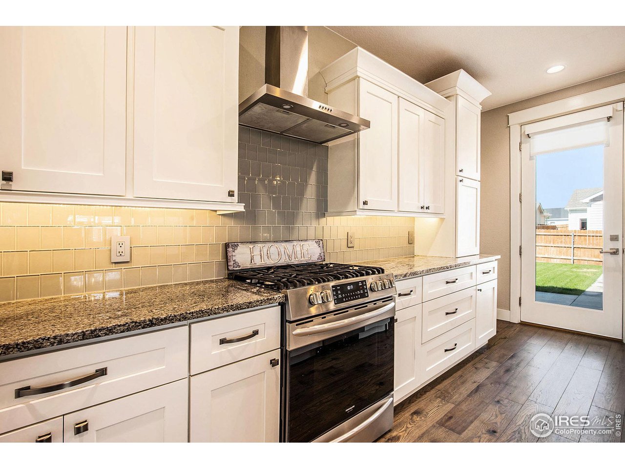 1100 Johnson Street Wiggins, CO 80654 - Photo 9 of 34 a kitchen with granite countertop a stove a sink and white cabinets with wooden floor