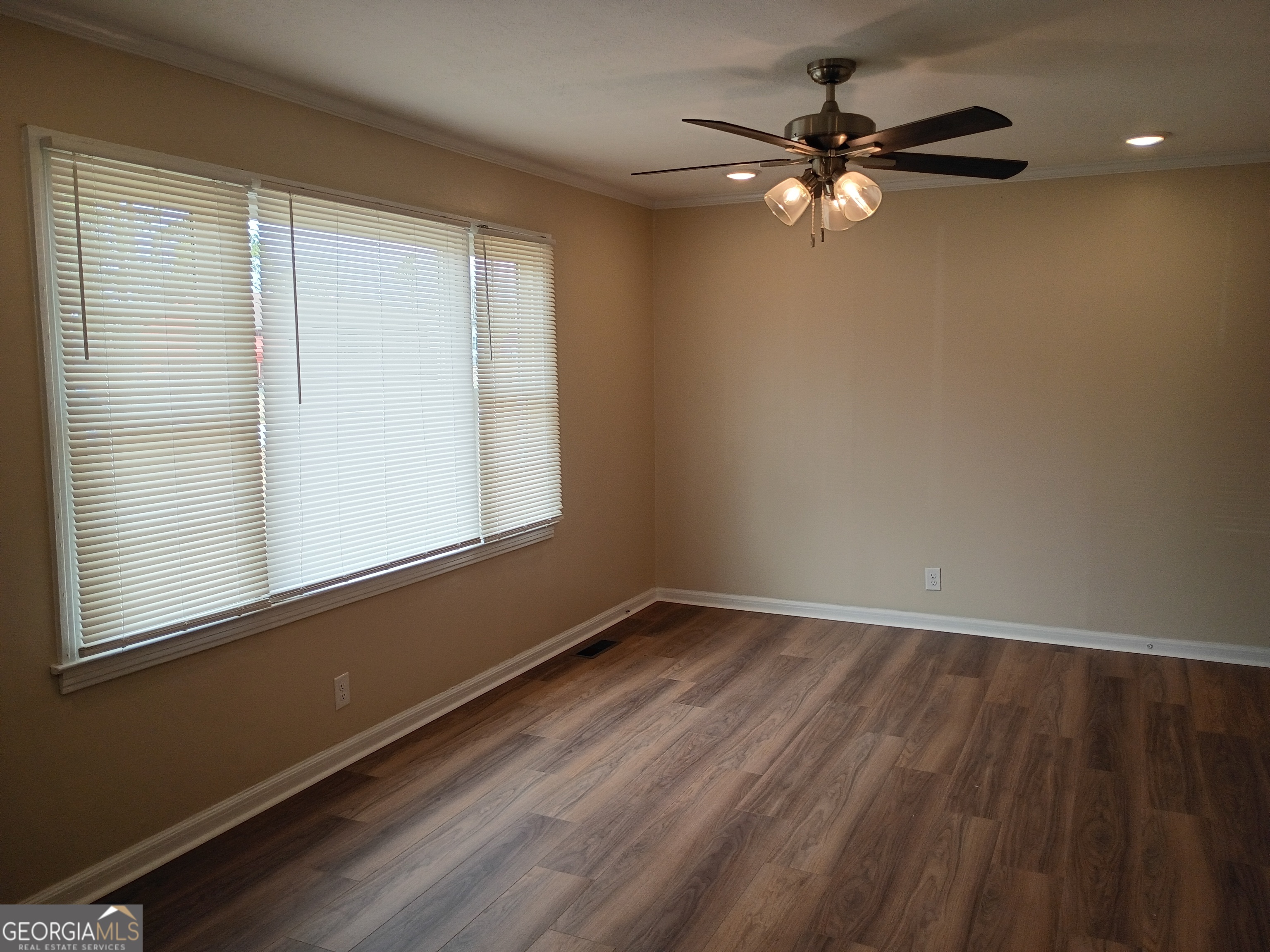 624 Thompson Road Swainsboro, GA 30401 - Photo 3 of 20 an empty room with wooden floor fan and windows
