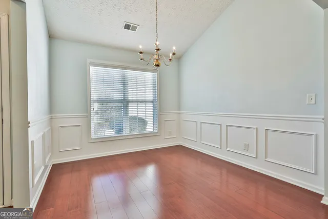 an empty room with chandelier fan and windows