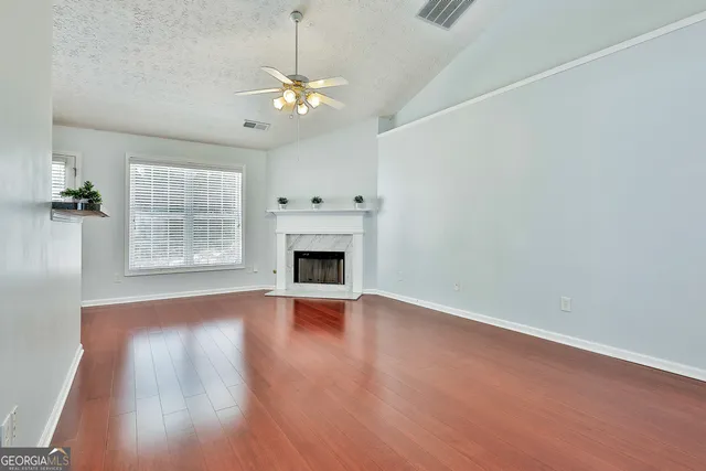 an empty room with wooden floor chandelier and windows