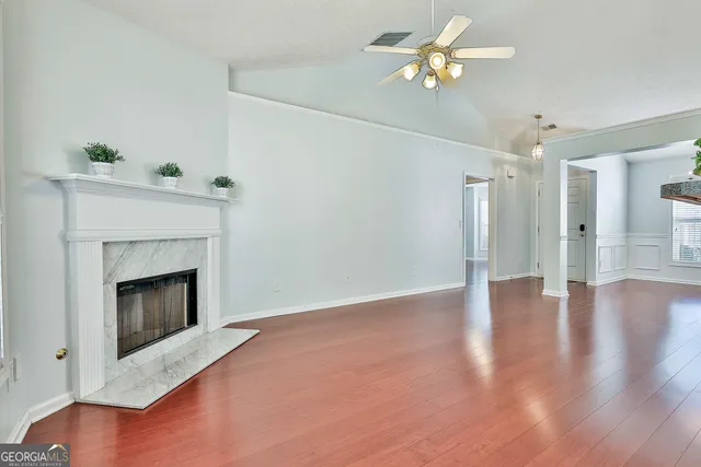 a view of an empty room with chandelier fan and wooden floor