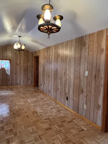 a view of a livingroom with a chandelier fan and kitchen view