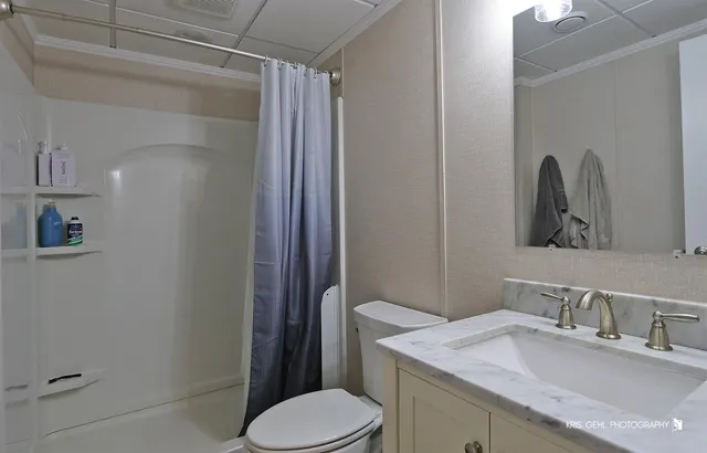 a bathroom with a granite countertop sink toilet and mirror