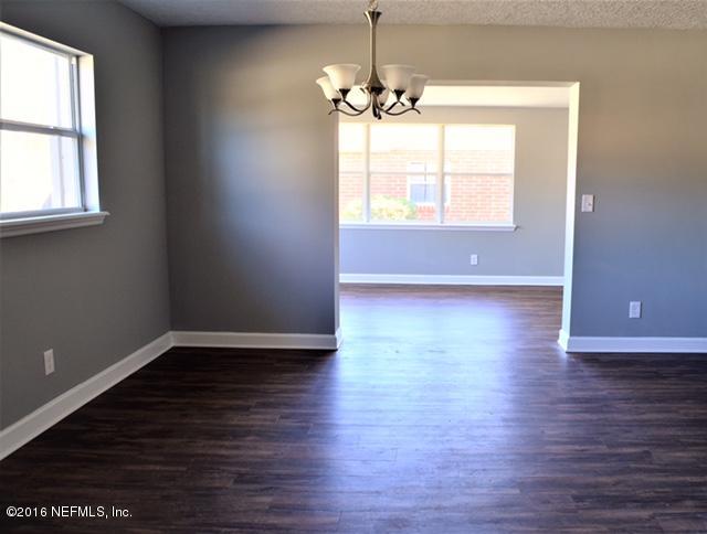 5520 Sabena Road Jacksonville, FL 32207 - Photo 7 of 8 an empty room with wooden floor chandelier and windows