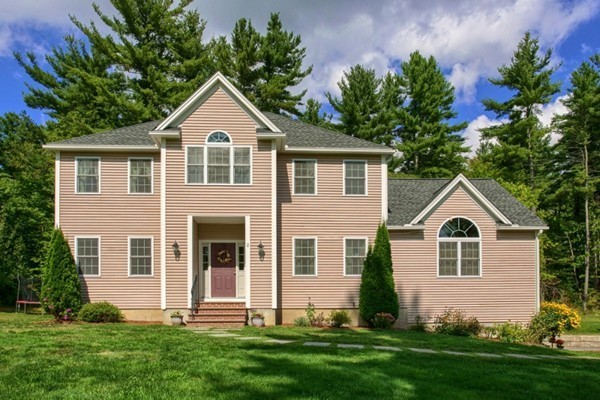 a front view of a house with a yard and trees