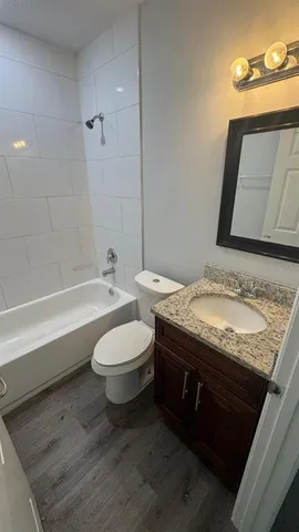 a bathroom with a granite countertop sink a toilet and bathtub