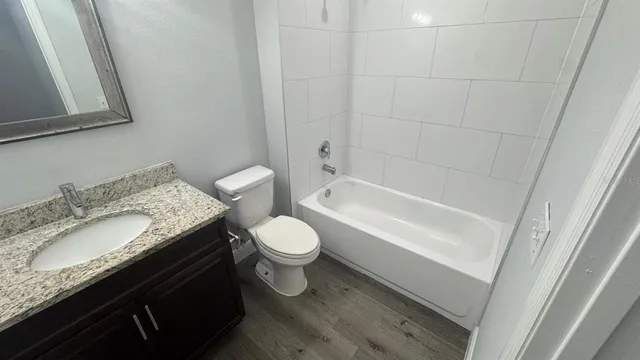 a bathroom with a granite countertop sink a toilet and bathtub