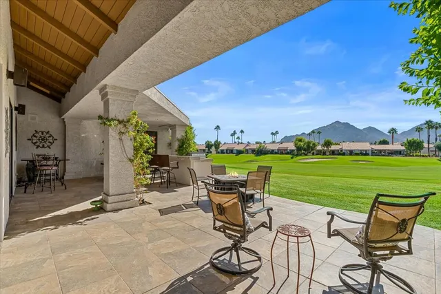 a view of a house with table and chairs under an umbrella in a patio
