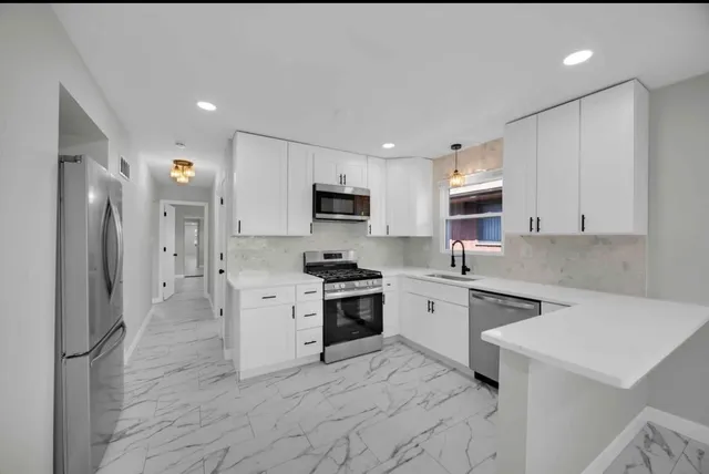 a kitchen with granite countertop a stove a sink and a refrigerator with wooden floors