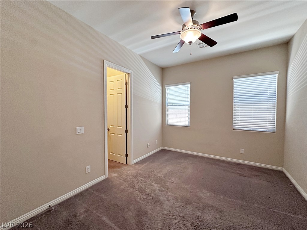 71 Newton Ridge Way Las Vegas, NV 89183 - Photo 23 of 40 A well-lit bedroom with soft carpet flooring and a ceiling fan for comfort.