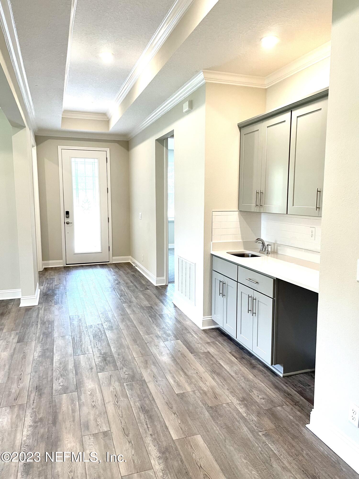 1521 Lake Foxmeadow Road Middleburg, FL 32068 - Photo 3 of 25 a large white kitchen with granite countertop a stove a sink and white cabinets with wooden floor