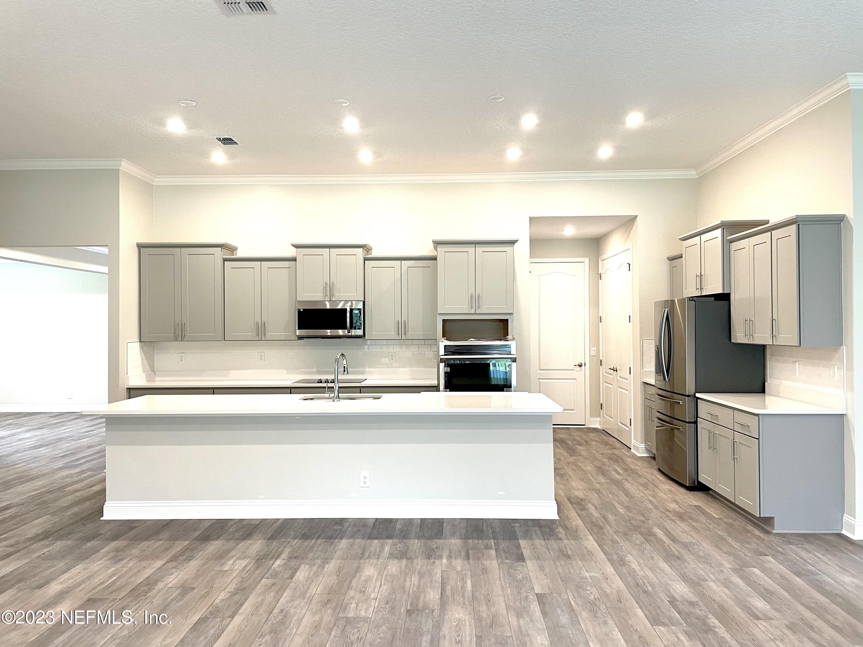 1521 Lake Foxmeadow Road Middleburg, FL 32068 - Photo 9 of 25 a large kitchen with kitchen island white cabinets and stainless steel appliances
