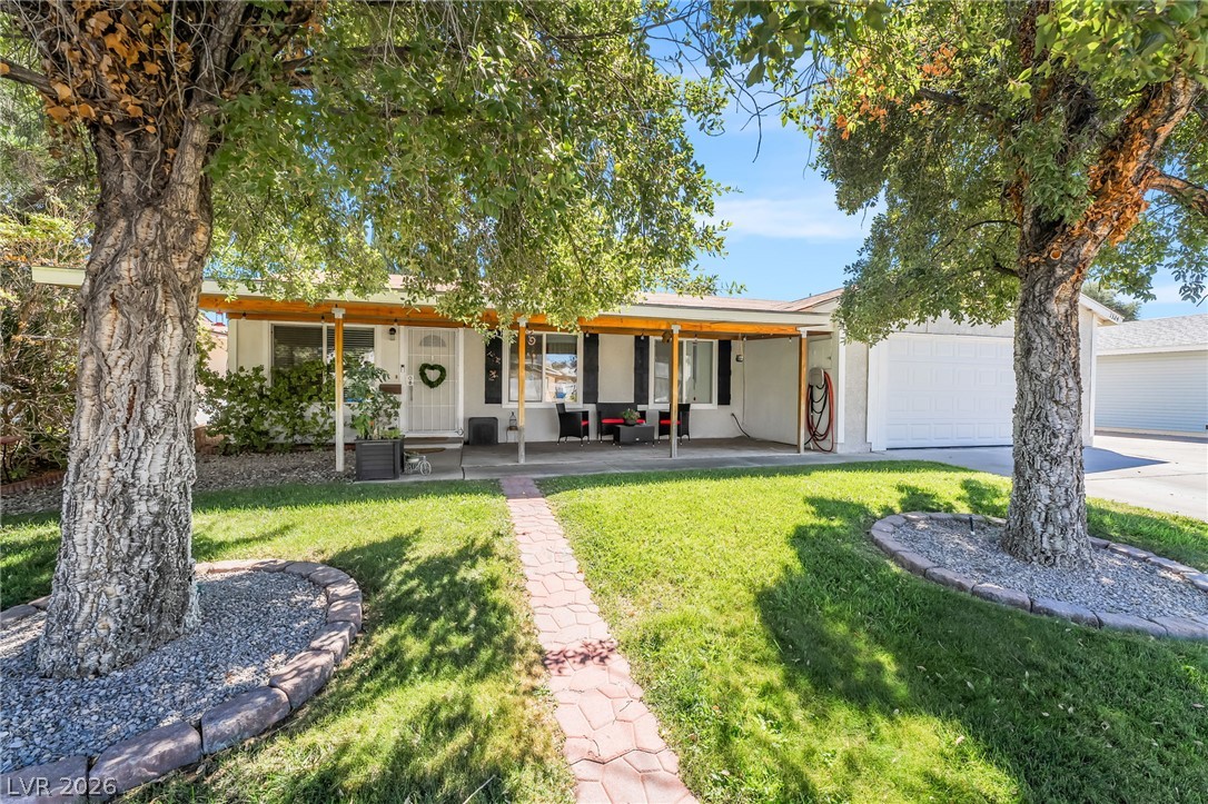 Mature shade trees flank a welcoming stone path leading to the covered front porch.