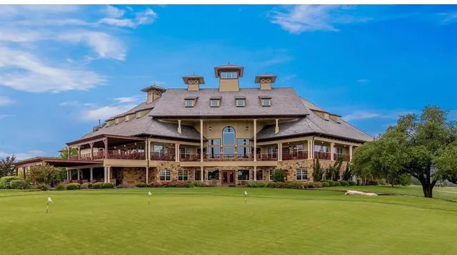 a view of a big house with a big yard and large trees