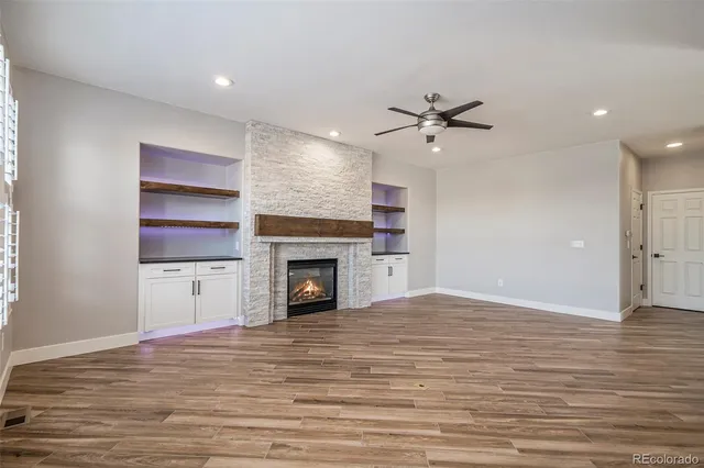 a view of an empty room with a fireplace and a ceiling fan