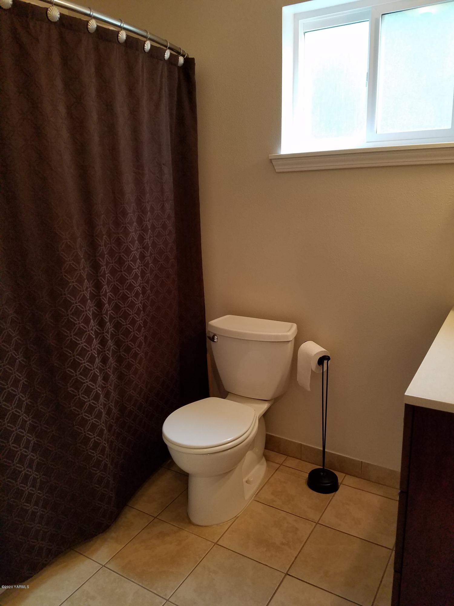 1920 South Euclid Road Grandview, WA 98930 - Photo 13 of 20 a bathroom with a toilet and a shower curtain