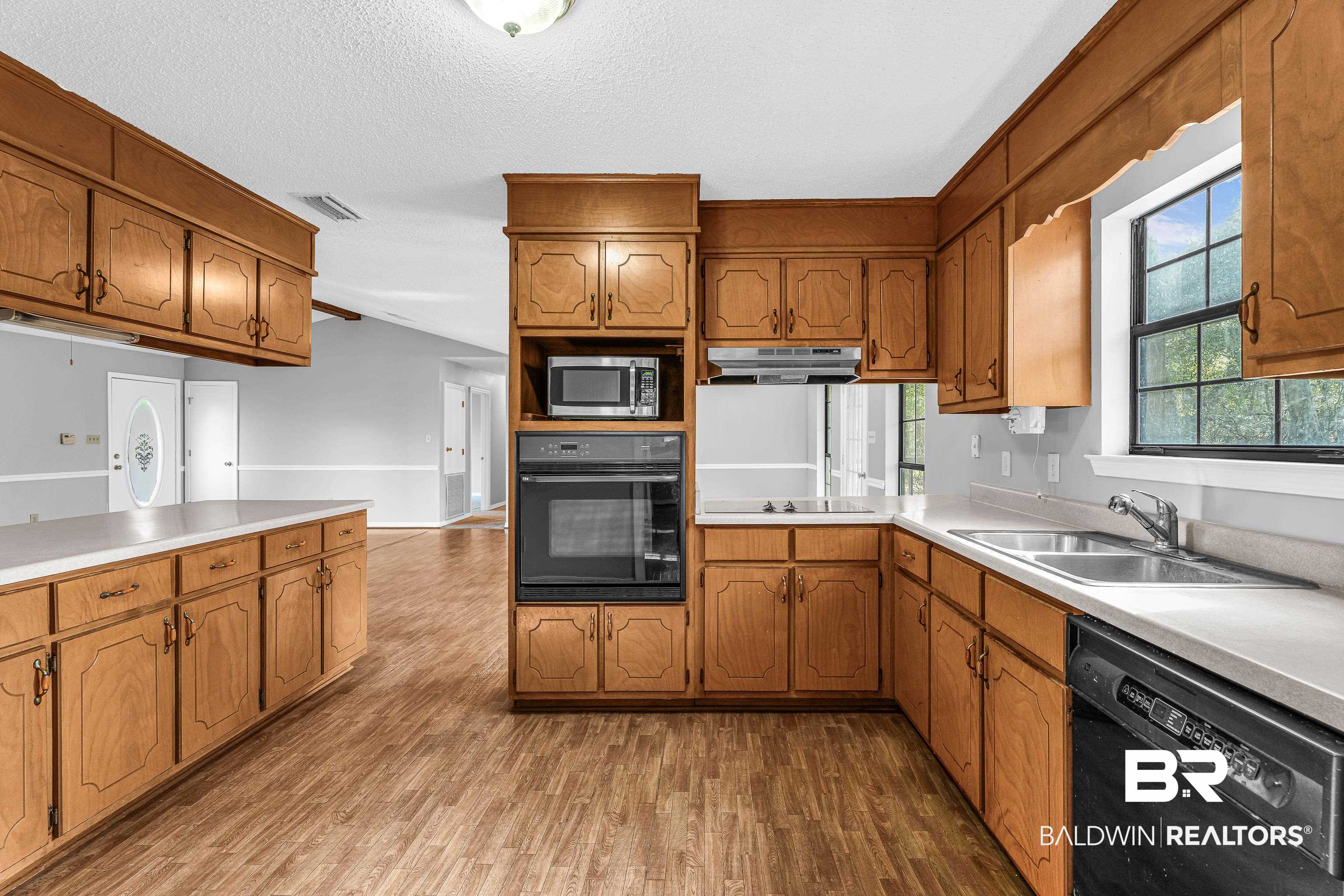7787 Bellingrath Road Theodore, AL 36582 - Photo 16 of 36 Kitchen featuring black appliances, light countertops, brown cabinetry, and a textured ceiling