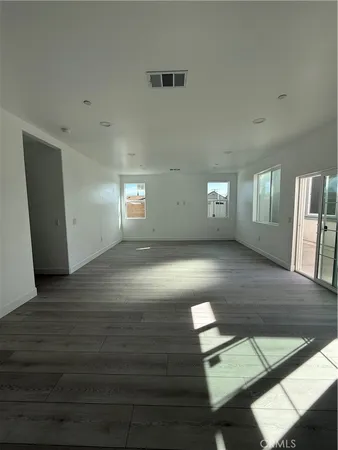 a view of an empty room with window and wooden floor