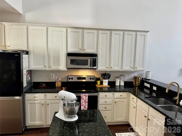 a kitchen with stainless steel appliances a stove a sink and white cabinets