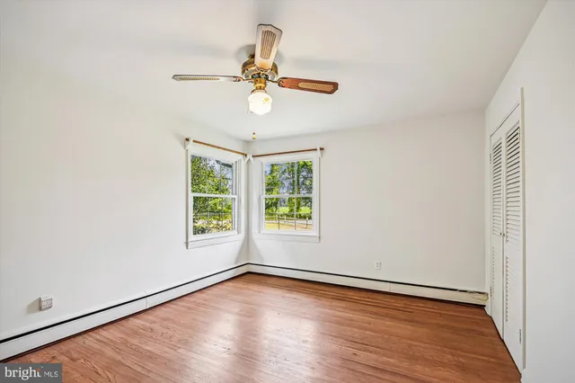 an empty room with wooden floor fan and windows