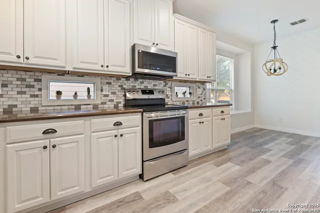 a kitchen with stainless steel appliances granite countertop a stove a sink and white cabinets