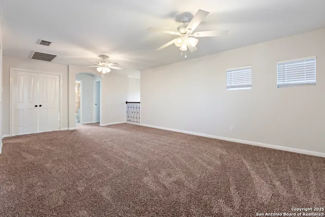 a view of an empty room with a chandelier fan