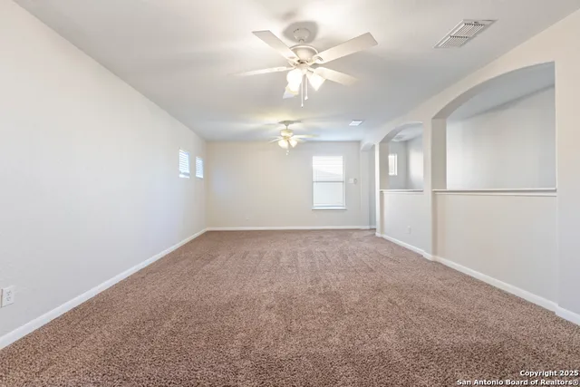 an empty room with windows and fan