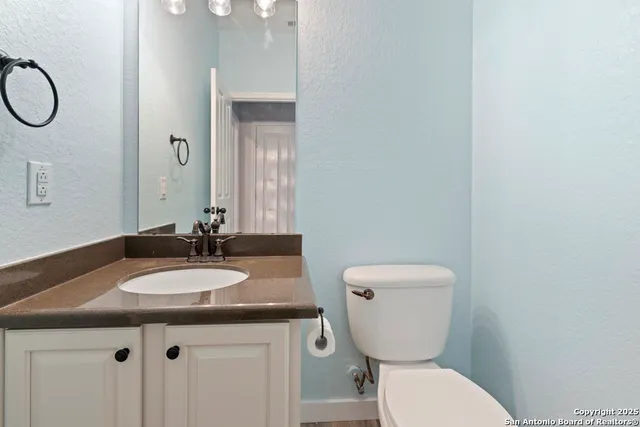 a bathroom with a granite countertop toilet sink and mirror