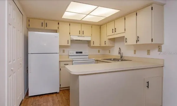 a kitchen with stainless steel appliances granite countertop a refrigerator sink and white cabinets