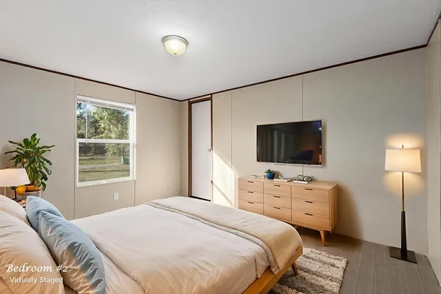 a bedroom with a bed a flat screen tv and a window