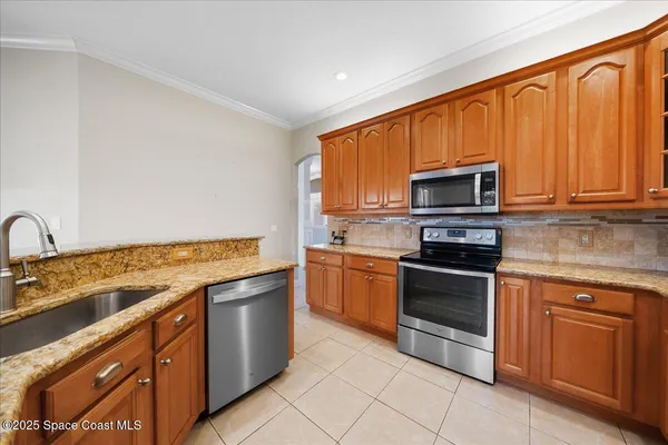 a kitchen with stainless steel appliances granite countertop a stove top oven a sink dishwasher and white cabinets with wooden floor