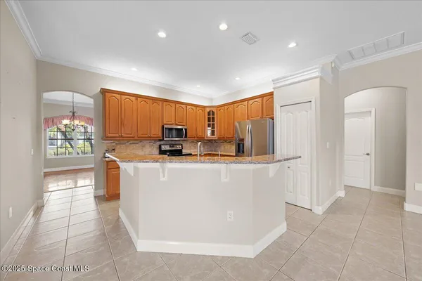 a living room with stainless steel appliances a refrigerator a sink a stove a microwave and cabinets