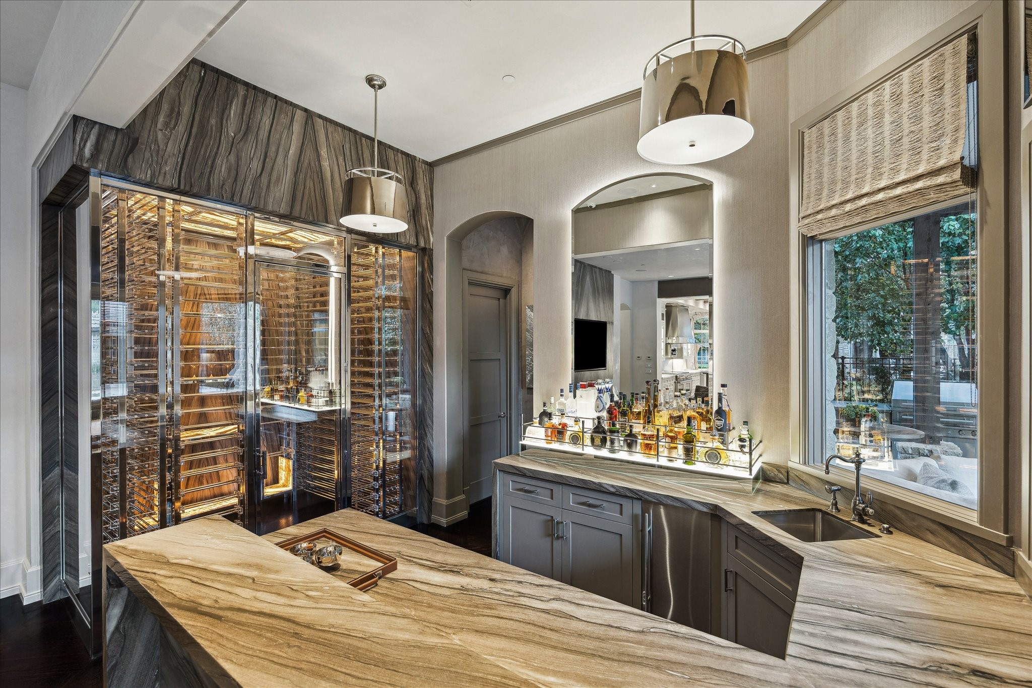 220 Merrie Way Lane Houston, TX 77024 - Photo 15 of 50 This custom bar blends sculptural design with function, featuring leathered marble counters with a waterfall edge, a top-hat ice machine, beverage fridge, dishwasher, and polished nickel fixture with filtered water.