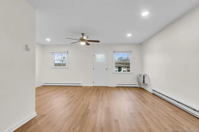 an empty room with wooden floor chandelier fan and windows