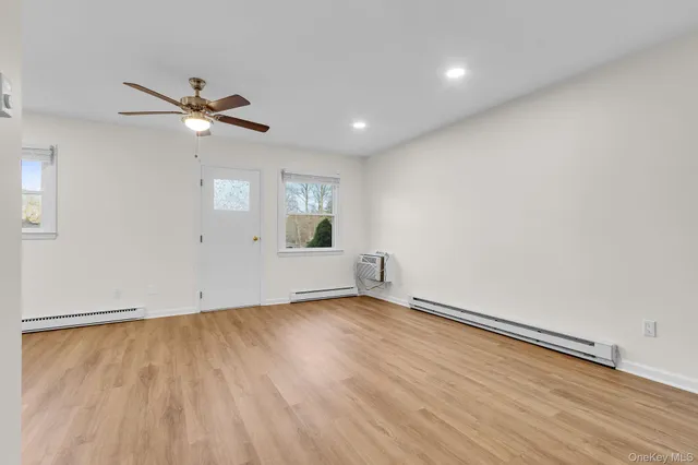 a view of empty room with wooden floor and fan