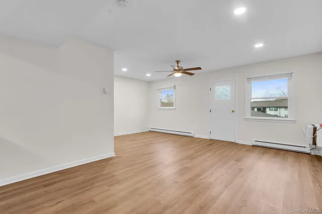 an empty room with wooden floor chandelier and windows