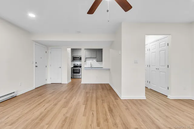 an empty room with wooden floor and a kitchen