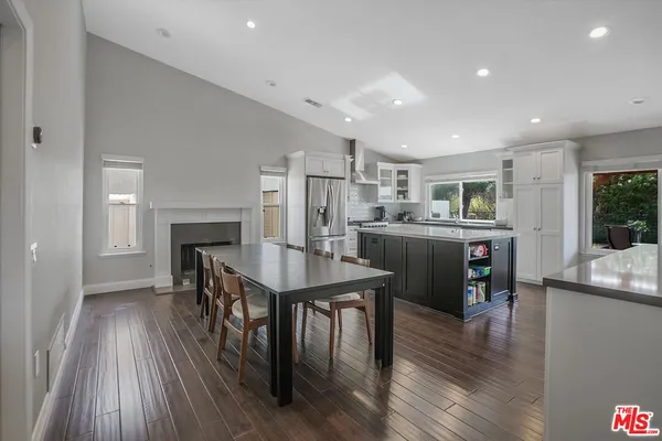 a kitchen with stainless steel appliances a dining table chairs and wooden floor