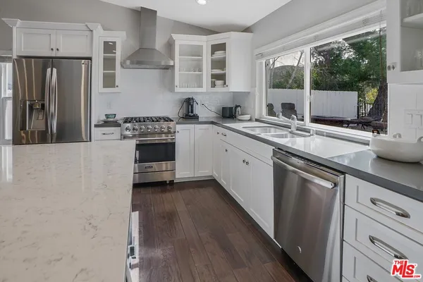 a kitchen with stainless steel appliances granite countertop a stove a sink and a refrigerator