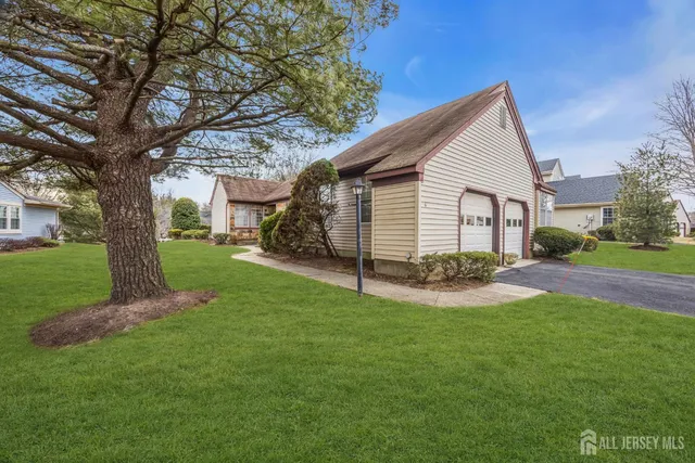 a view of a house with a yard and a large tree