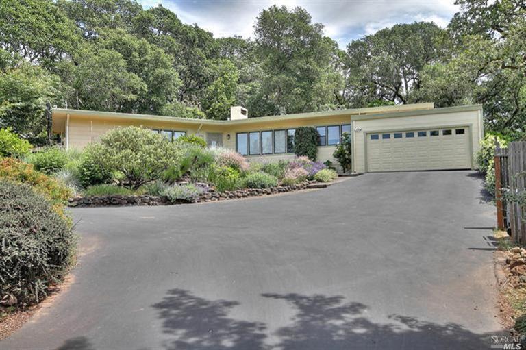 4740 Sullivan Way from street entry. Paved driveway and terraced garden provide welcome, with 2-car garage at top of driveway. This home has two fireplaces: one wood-burning (chimney seen here) and a gas-insert in the master suite.