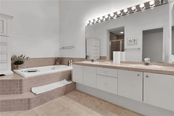 a spacious bathroom with a tub double sink and mirror